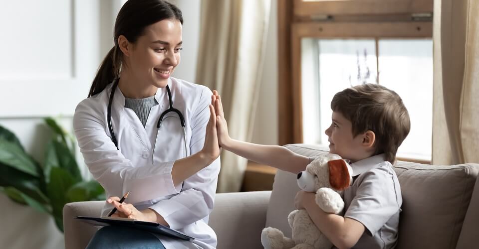Smiling woman doctor or nurse give high five to excited little boy patient at consultation in clinic, happy small child have fun greet with female pediatrician in hospital, healthcare concept